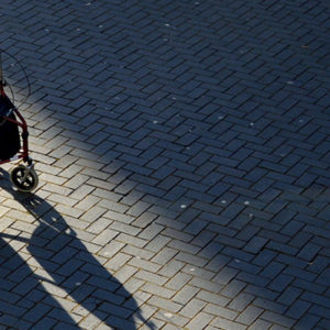 elderly person walking with support of trolley