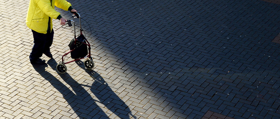 elderly person walking with support of trolley